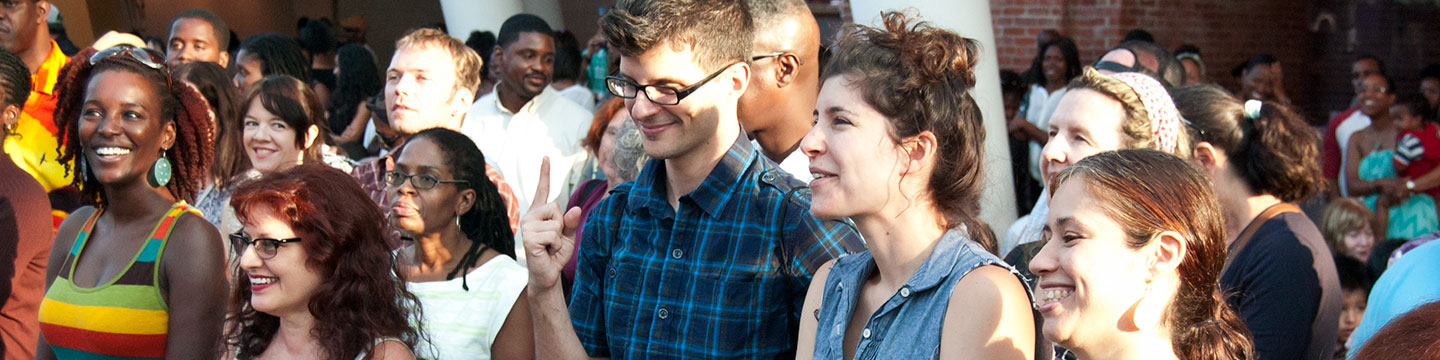 A large standing audience of visitors at First Saturdays